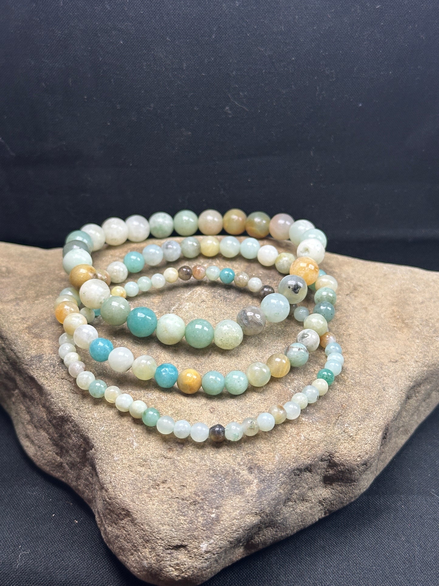 Close-up image of a 3-pack amazonite bracelet set from Alexis Home Goods, featuring beads in 4mm, 6mm, and 8mm sizes. Each bracelet showcases the soothing shades of aqua, teal, and pale green characteristic of amazonite stones, celebrated for their calming and communication-enhancing properties. The stretchy design ensures a comfortable fit for most wrist sizes.