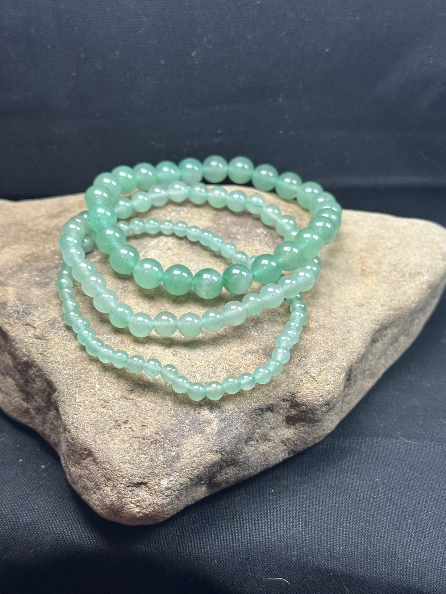 Close-up image of a 3-pack green aventurine bracelet set from Alexis Home Goods, featuring beads in 4mm, 6mm, and 8mm sizes. Each bracelet showcases the vibrant green tones of aventurine stones, known for their connection to luck, prosperity, and heart-centered energy. The stretchy design ensures a comfortable fit for most wrist sizes.