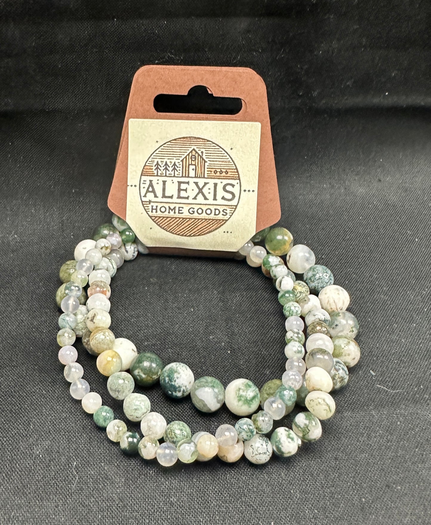 Close-up image of a 3-pack tree agate bracelet set from Alexis Home Goods, featuring beads in 4mm, 6mm, and 8mm sizes. Each bracelet highlights the natural green and white marbled patterns of tree agate stones, symbolizing growth and balance. The stretchy design ensures a comfortable fit for most wrist sizes.